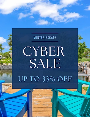 A blue ad sign on a sunny dock promoting a winter escape cyber sale, up to 33% off, with colorful chairs in the foreground.